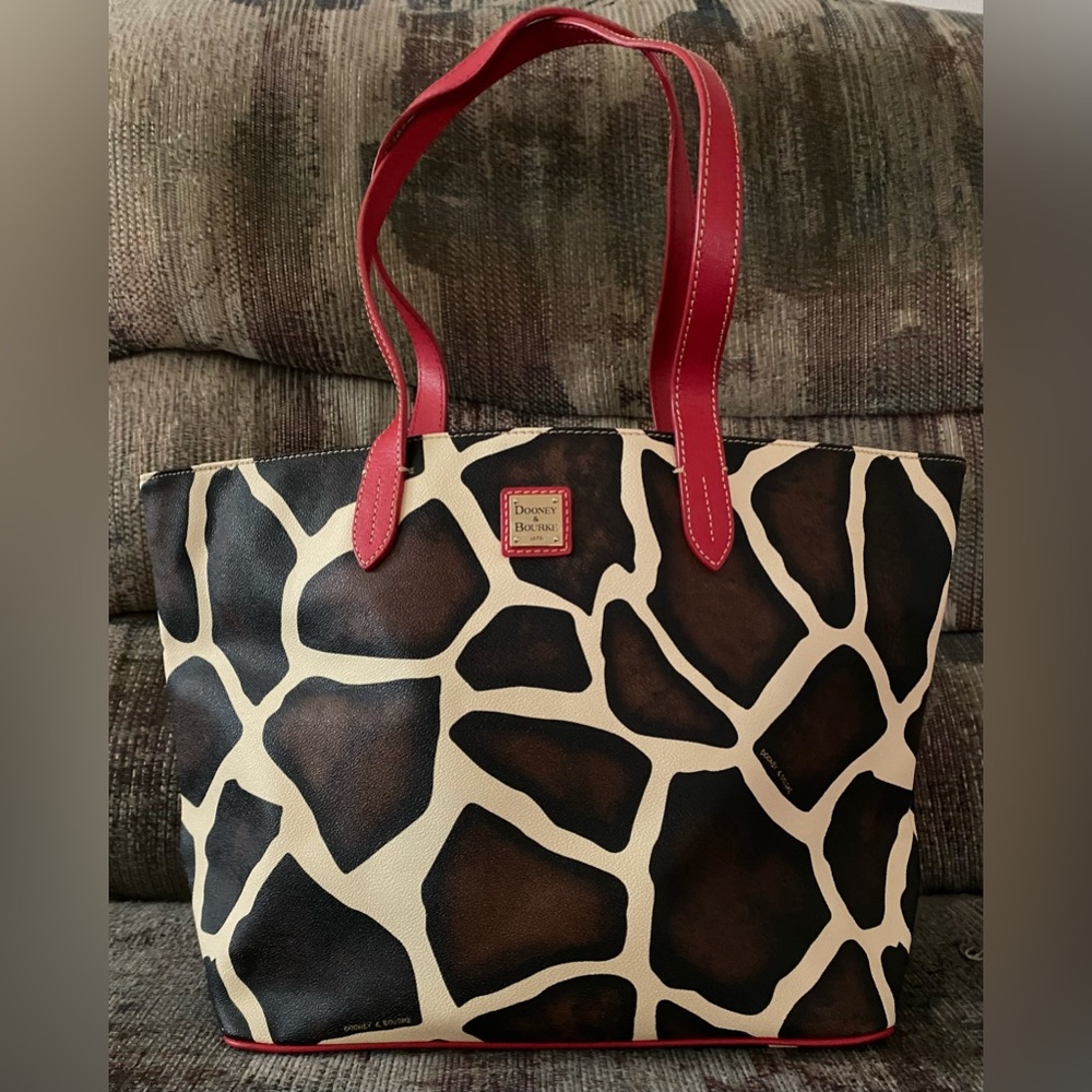 Dooney & Bourke giraffe print tote with red strap.